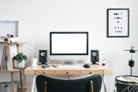 White scandinavian interior of home desk with mock up computer screen, office accessories, speakers, vinyl recoreder and setup of drums . Minimalistic space for work, hobby and listen music. 
