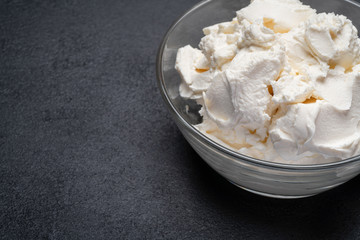 Traditional Mascarpone cheese in glass bowl on concrete background