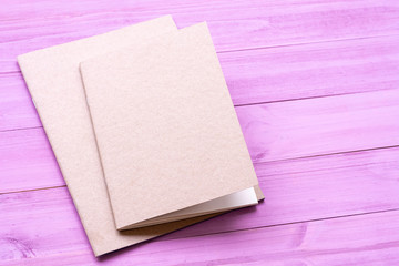 Fototapeta premium Two brown notebook isolated on violet wooden background.