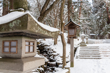 Japanese stone and wooden lantern with snow at Hida-sannogu Hie-Jinja shrine in winter season . At Gifu , Hida Takayama , Japan .