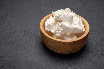Traditional Mascarpone cheese in wooden bowl on concrete background