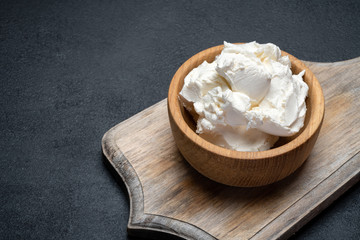 Traditional Mascarpone cheese in wooden bowl on concrete background