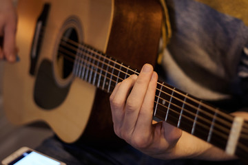 Fototapeta na wymiar The singer plays the song on an acoustic guitar, holding on his knee smartphone, which is written lyrics