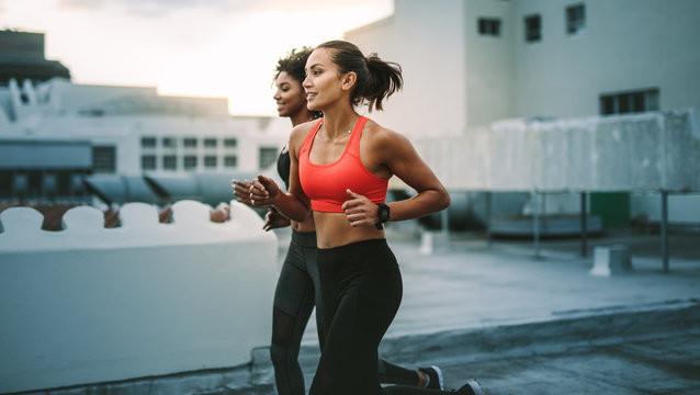 Fitness women running together on rooftop