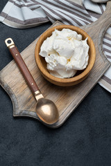Traditional Mascarpone cheese in wooden bowl on concrete background