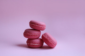 Four pink macaroons on a light pink background, sweet minimal food concept