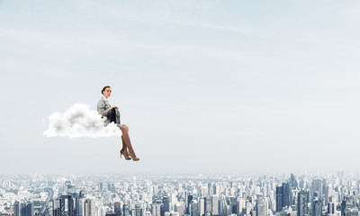 Businesswoman or accountant on cloud floating high above modern city