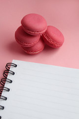 Four living coral macaroons, empty notebook on a light pink background
