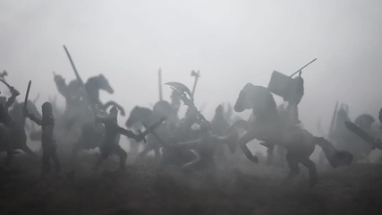 Medieval battle scene with cavalry and infantry. Silhouettes of figures as separate objects, fight between warriors on sunset foggy background. Artwork decoration. Selective focus