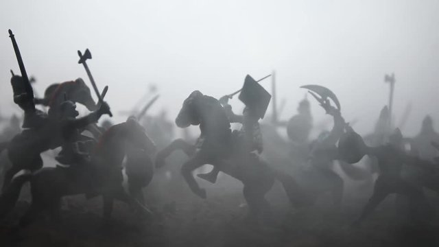 Medieval battle scene with cavalry and infantry. Silhouettes of figures as separate objects, fight between warriors on sunset foggy background. Artwork decoration. Selective focus