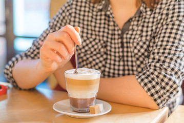 a woman in a cafe stirring a spoon of espresso