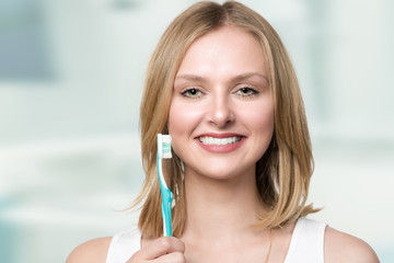 Junge Frau hält eine Zahnbürste und lächelt