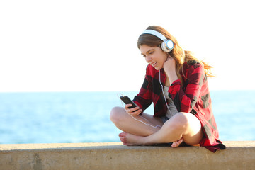 Happy teenage female listening to music from smart phone