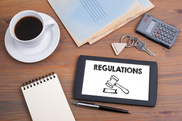 Regulations concept. Text and icon on tablet device on a wooden table