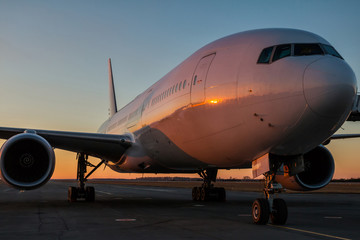 White wide body passenger aircraft at the airport apron in the evening sun