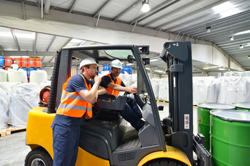 Arbeiter in der Logistik im Warenlager // Discussion of workers in a warehouse at a forklift truck on the subject of work safety 