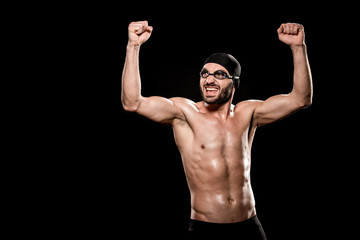 Fototapeta na wymiar cheerful swimmer standing in swimming cap and celebrating victory isolated on black
