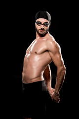 Fototapeta na wymiar muscular swimmer posing in swimming cap and goggles isolated on black