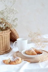 Breakfast table with a cup of coffee and croissants, light and bright mood