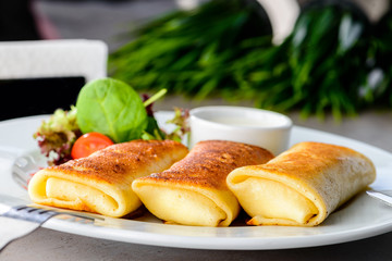 Appetizing pancakes (blinis) with sour cream on the table. New menu for the restaurant