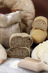 Different kinds of bread and bread rolls on board from above on wooden table