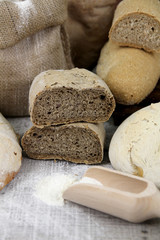 Different kinds of bread and bread rolls on board from above on wooden table