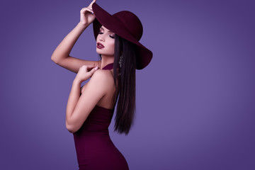 Elegant beautiful brunette woman in a violet dress and wide hat