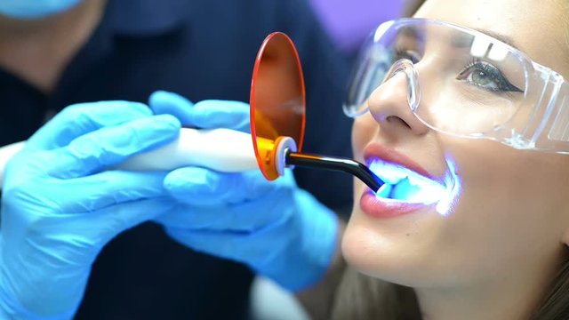 Dentist using ultraviolet lamp on a female patient