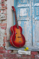 Acoustic old guitar against the background of blue shutters