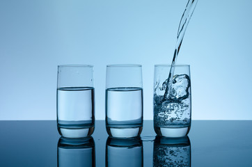 Creative splashing water in the glass on blue background.