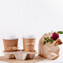 Two paper cups of coffee in cardboard tray on white background. Take out food. Cups with face of man and woman, couple in love, relations, love concept. Happy Valentine's day. Copy space.