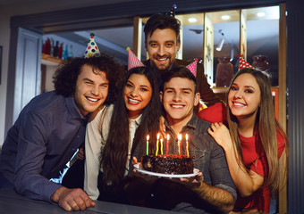 Group of friends celebrating birthday with birthday cake at restaurant