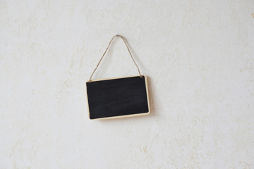 small blank chalkboard sign with piece of string hanging on nail                             