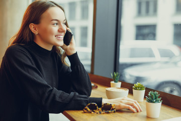 Woman Wear Glasses, Talk At Phone, Drink Her Hot Coffee While Work In Cafe On Her Laptop. Portrait Of Stylish Smiling Woman In Winter Clothes Drinking Hot Coffee And Work At Laptop. - Image