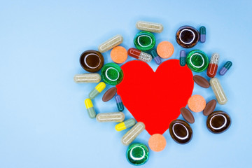 Different medications for the heart. Conceptual background on the pharmaceutical theme on a blue background is lined with a heart from different multi-colored pills, close-up pills for cardiology.