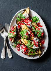 Grilled eggplant with feta, cilantro and pomegranate seeds on dark background, top view. Delicious snack, tapas, appetizers