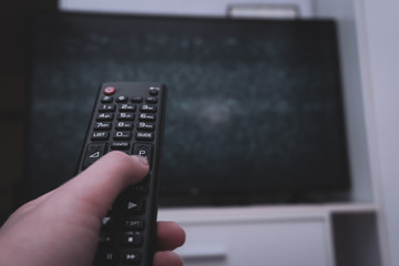 Female holding TV remote control in front of TV. Couch potatoe. Point of view shot.