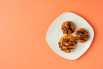 Traditional French dessert. Eclair with chocolate icing. Pastry concept on coral color background. Flat lay or top view.