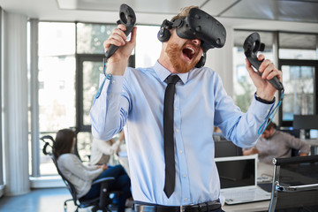 Fototapeta na wymiar Employee in formal wear trying out VR technology in office. In background other employees working.