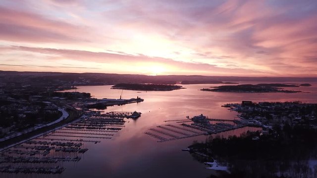 Crane uplifting aerial shot towards Oslo center and fjord in Norway at sunset