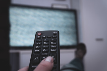 Female holding TV remote control in front of TV. Couch potatoe. Point of view shot.