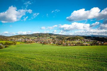Obraz premium A view of the hill called Helfštýn on the field and the surrounding can be seen village Krhová during a sunny day with many colored clouds