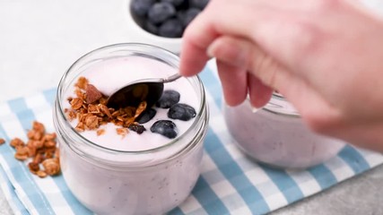 Eating blueberry yogurt. Healthy breakfast or snack. Woman eating yogurt