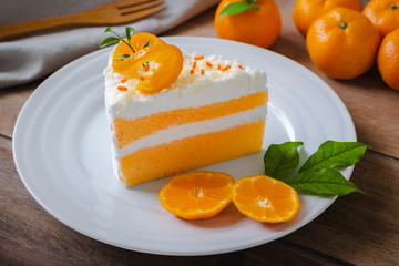 Orange cake and fresh orange on white plate .