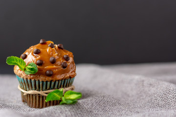 chocolate muffin, easter cake, caramel sauce, chocolate drops, chocolate cake on gray napkin. served with mint in rustic style.