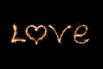 Love word written by sparklers on a black background.