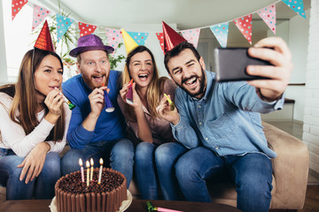 Young group of happy friends celebrating birthday at home make selfie photo.