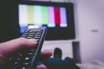 Female holding TV remote control in front of TV. Couch potatoe. Point of view shot.