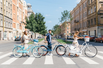 Obraz premium Best friends with retro bicycles cross the road, enjoying carefree time with friends, safe road crossing, urban transport, joyful time/ summertime, leisure and lifestyle concept.