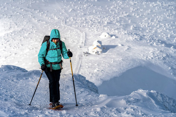 Fototapeta na wymiar Winter sport activity. Woman hiker hiking with backpack and snowshoes snowshoeing on snow trail.